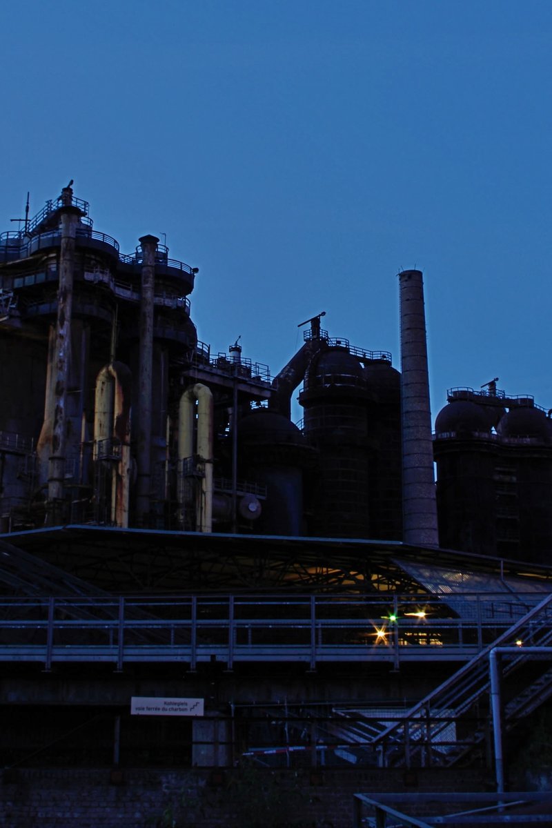 The blast furnaces and towers of Völklingen Ironworks at dusk against a deep blue sky, Saarland, Germany